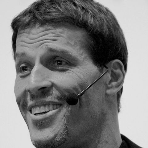 Retrato de Tony Robbins sorrindo, com microfone de cabeça